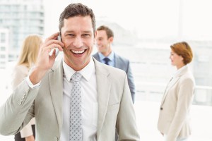 Portrait of businessman using mobile phone with colleagues behind in office