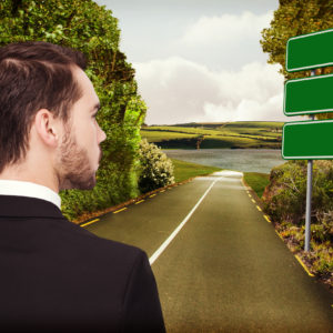 Elegant businessman in suit thinking  against green signs by road