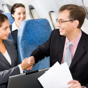 Photo of businessmen and businesswoman shaking hands in a plane