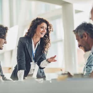 Young happy CEO communicating with her colleagues on a meeting in the office.