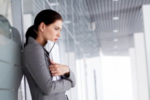 Pensive businesswoman with documents by wall