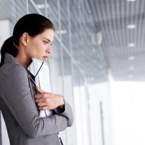 Pensive businesswoman with documents by wall