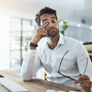 Shot of a young businessman looking stressed out and tired while working in an office