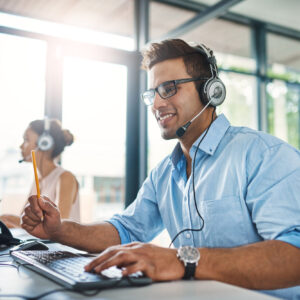 Cropped shot of a handsome young man working in a call center with a female colleague in the background